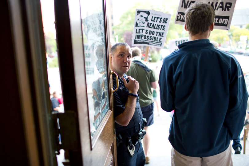 An SPD officer watches as Occupy Syracuse members leave city hall.
