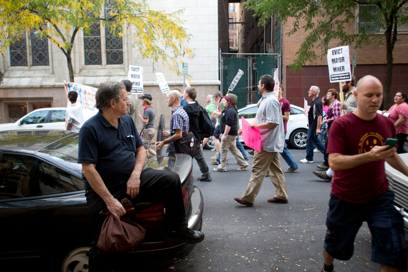 A man sat on his car and watched the Occupy march go by.