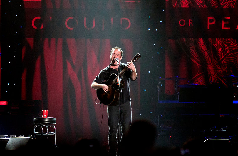 Dave Matthews performs at the center of the stage.
