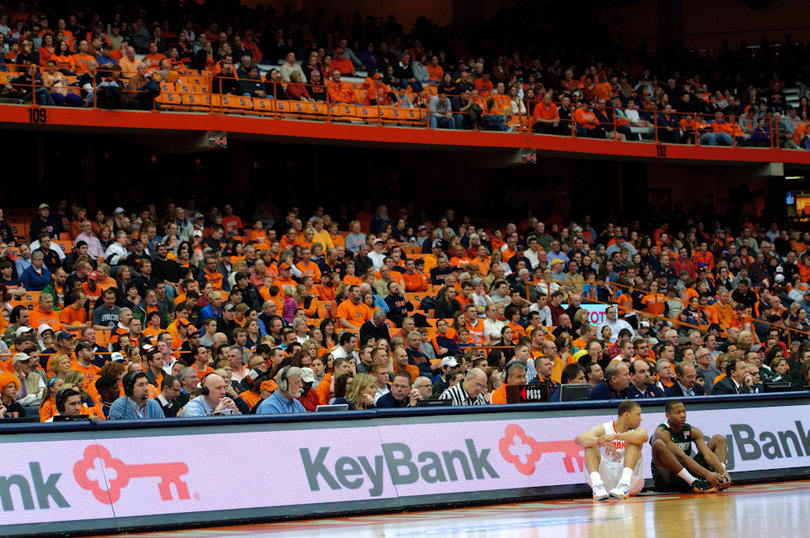 Syracuse guard Brandon Triche sits at the scorer's table before entering as the home crowd for SU's first home game of the season looks on.