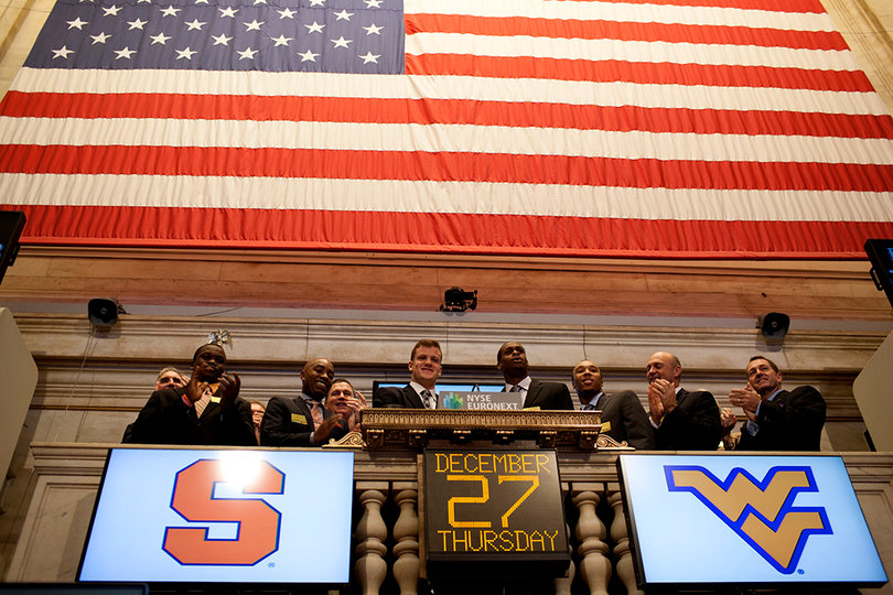 Syracuse quarterback Ryan Nassib and West Virginia quarterback Geno Smith stand in the center of representatives from both teams as they ring the opening bell at the New York Stock Exchange.
