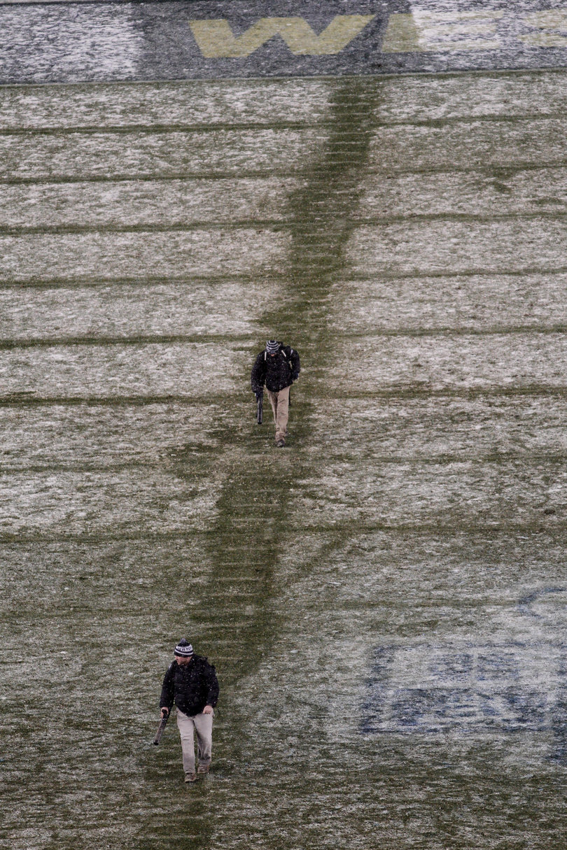 Workers blow snow off the lines on the field in the fourth quarter. 