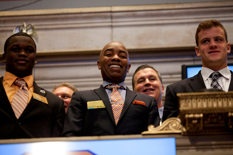 (From left) Geno Smith, Daryl Gross and Ryan Nassib stand on a platform overlooking the New York Stock Exchange. The three among representatives from Syracuse and West Virginia to ring the opening bell at the stock exchange Thursday morning.