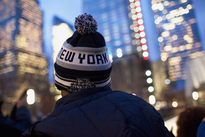 A Syracuse football player dons a winter hat with the words "New York" and the Pinstripe Bowl emblem on it.