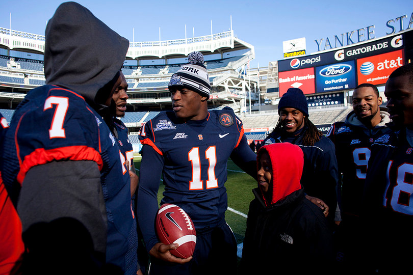 Syracuse linebacker Marquis Spruill stands with a child at Friday's "chalk talk" at Yankee Stadium.
