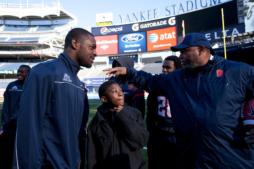 Syracuse cornerback Keon Lyn and secondary coach Donnie Henderson chat with a child attending the "chalk talk" at Yankee Stadium Friday.