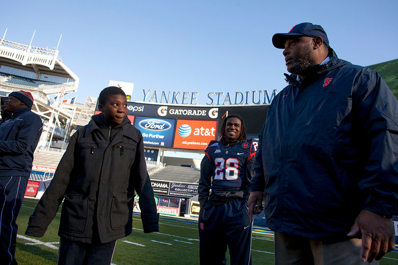 Secondary coach Donnie Henderson speaks with a child at Friday's "chalk talk" as safety Jeremi Wilkes (28) laughs in the background.