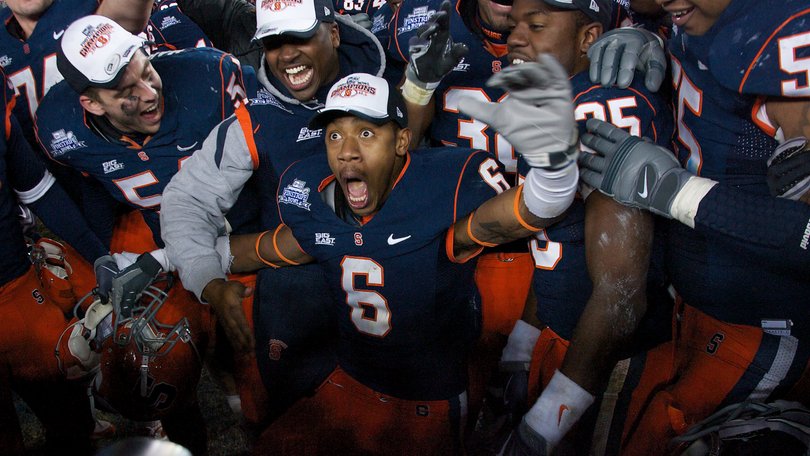 Da'Mon Merkerson celebrates at the center of a huddle of Syracuse football players after the Orange won the inaugural Pinstripe Bowl over Kansas State.