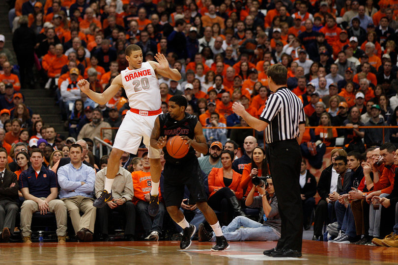 Syracuse guard Brandon Triche attempts to block a shot, as Cincinnati guard JaQuon Parker tries to duck under him.