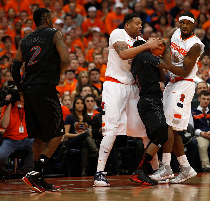 Syracuse forwards DaJuan Coleman and C.J. Fair surround Cincinnati guard Cashmere Wright in an attempt to steal the ball.