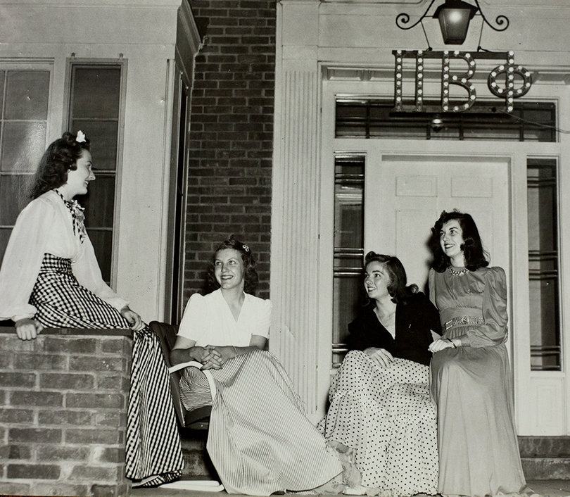 Pi Phi sisters from 1940 socialize on the porch of the current house at 210 Walnut Pl.