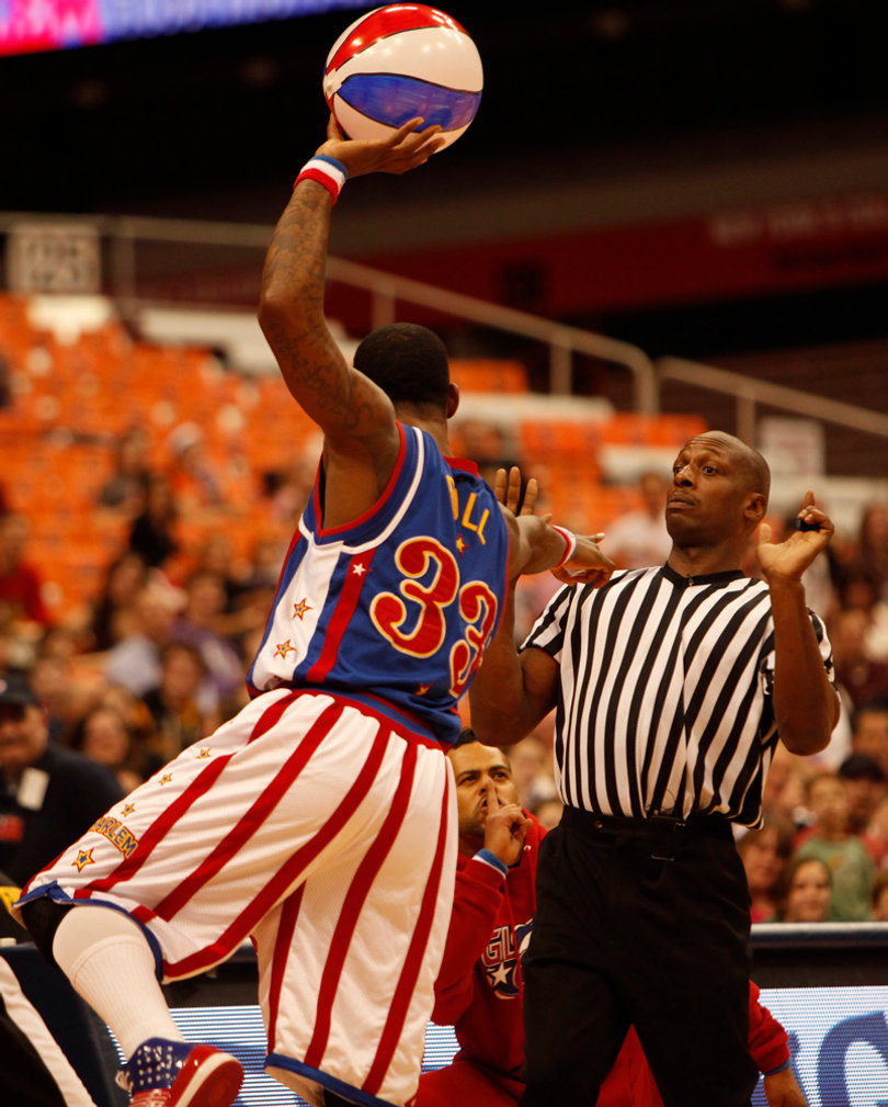 Bull points accusingly at the refere as a Globetrotter dancer looks on in the background. 