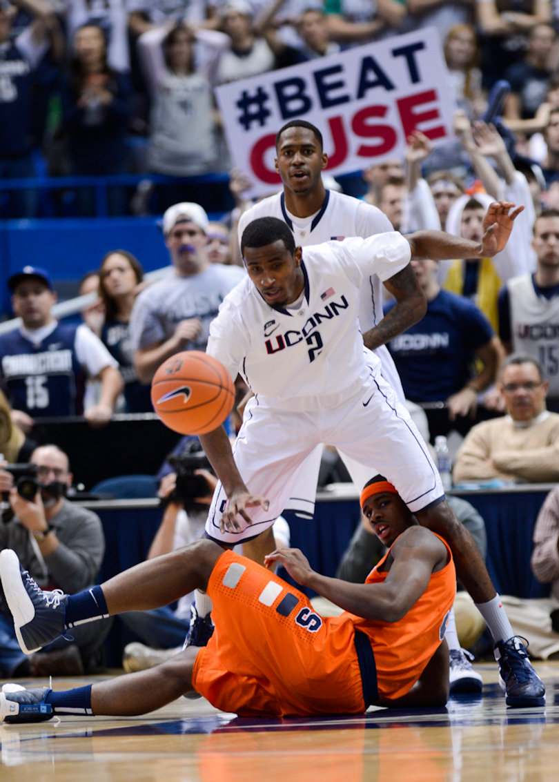 Connecticut forward DeAndre Daniels reaches for a loose ball after Syracuse small forward C.J. Fair falls between his legs.