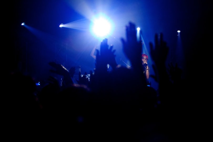 Big Sean is seen through the raised hands of members of the crowd.