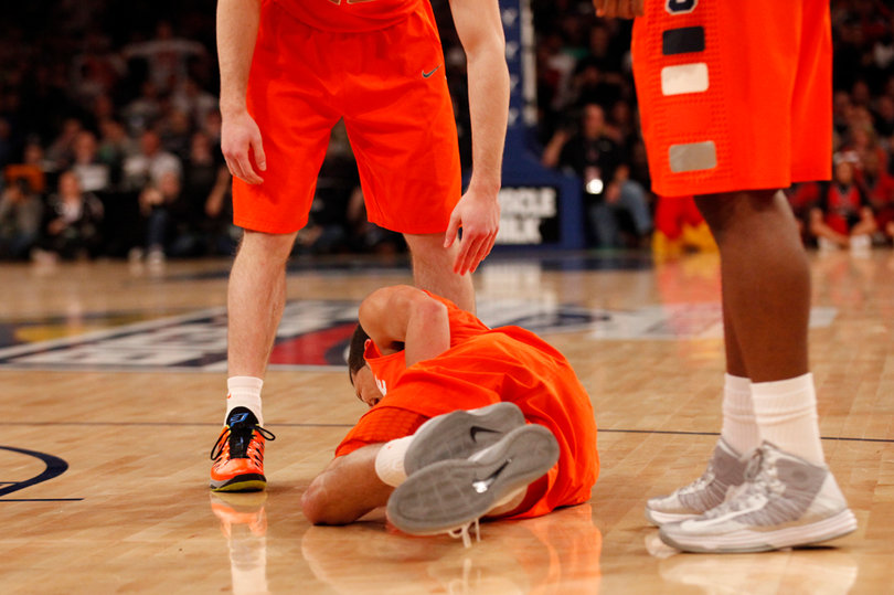 Michael Carter-Williams falls to the ground after taking a hit to the gut.