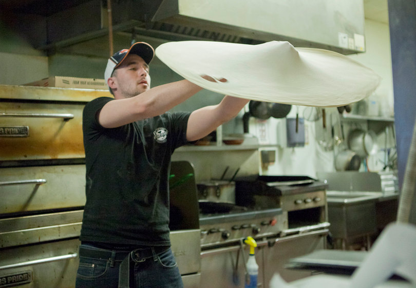 Michael Lagneaux, an employee of Siracusa's, prepares a pizza by tossing dough.