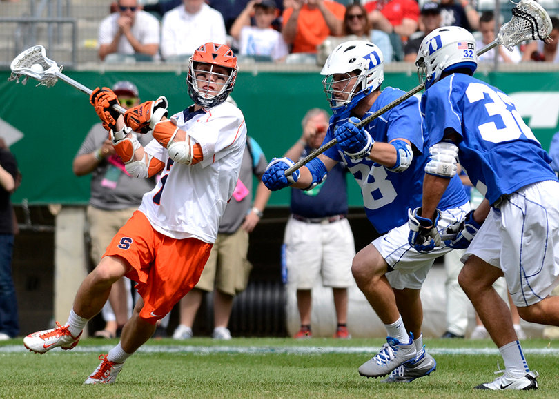 A Syracuse player slides by two Duke defenders and winds up to shoot.