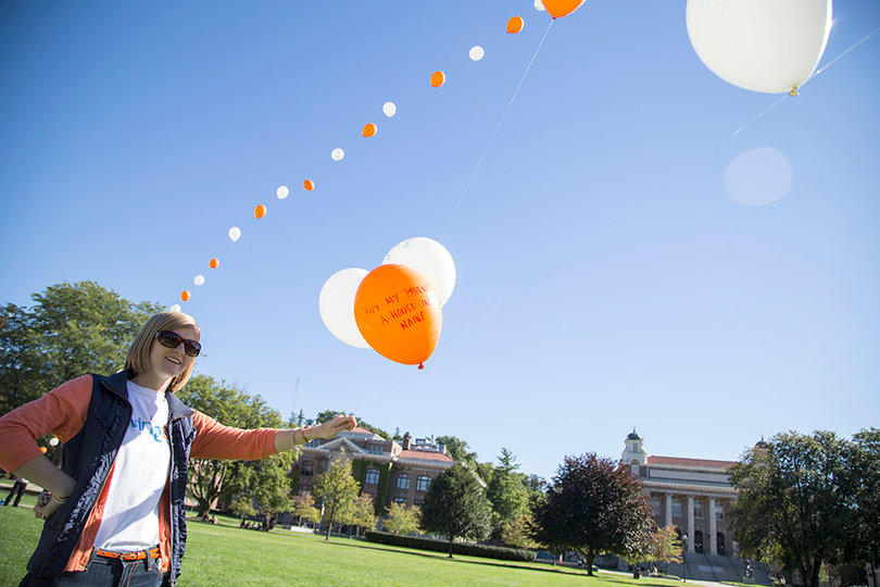 Meghan Ross, a junior communications and rhetorical studies major and communications assistant for Living SU holds down the line of balloons before they are launched into the air.
