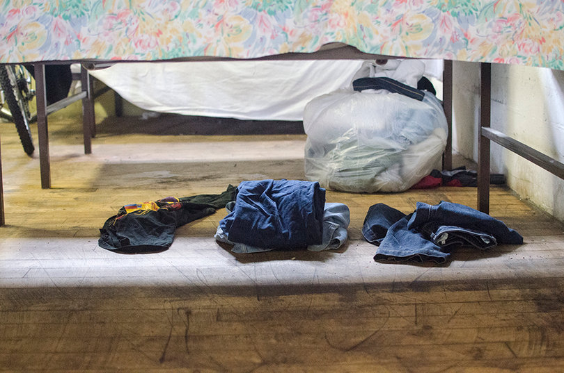 A set of clothes for the inn’s residents lay underneath a bed inside the shelter. 