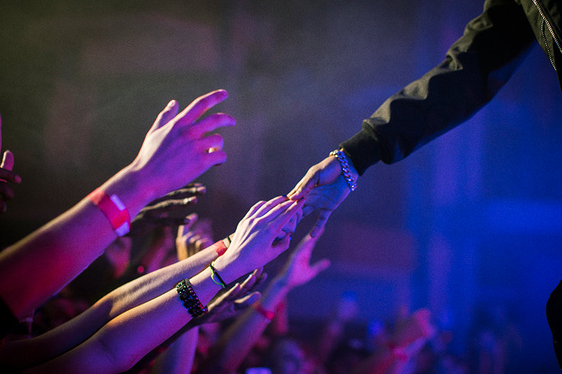 Big Sean interacts with the crowd as he reaches out and holds hands with audience members in the front row. 