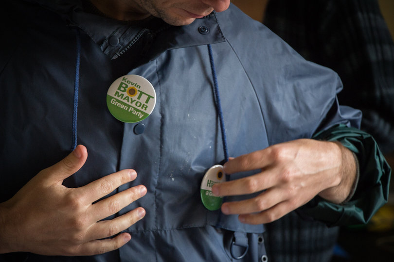 Derek Mason, a party member, shows his support by adding pins to his jacket.