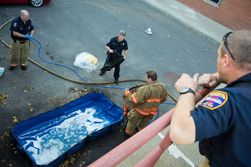 A member of the fire department watches as Hazmat gear is washed down in a portable bath stationed outside the Life Science Complex.