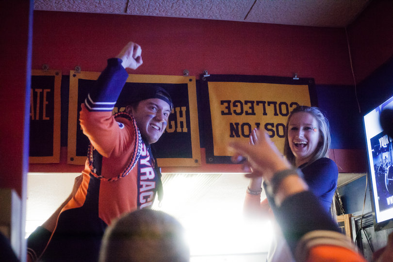(FROM LEFT) David Fagen, a senior saxophone player for the SU marching band, and Natasha Olejar, a senior color guard, turn over the Boston College flag inside of Varsity signifying the Syracuse University's victory. Fans packed into the restaurant to celebrate the win and the team's bowl eligibility.