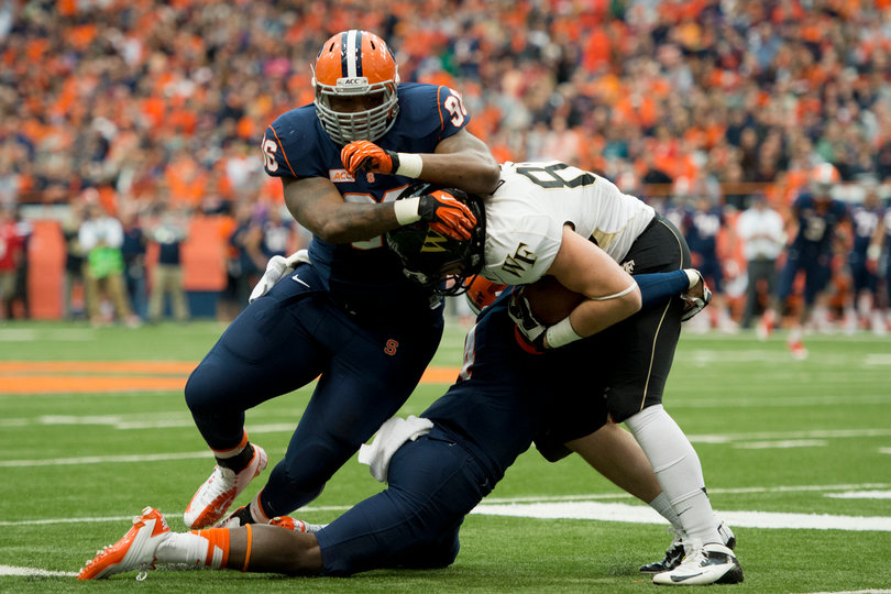 Orange defensive tackle Jay Bromley helps cornerback Brandon Reddish drag down a Demon Deacon.