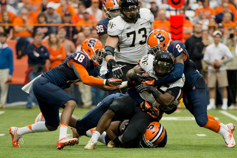 (From left) Syracuse defensive backs Darius Kelly and Wayne Morgan converge to bring down WFU tailback Josh Harris.