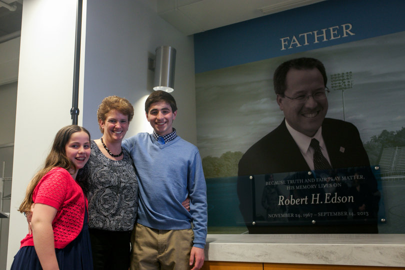 The Edson family stands by an image of Rob on a wall near Onondaga Community College's athletics' wall of fame.