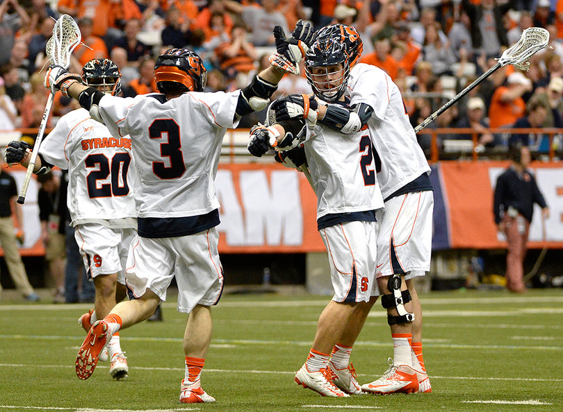 Ward raises his arm and embraces teammates after  a Syracuse goal. 