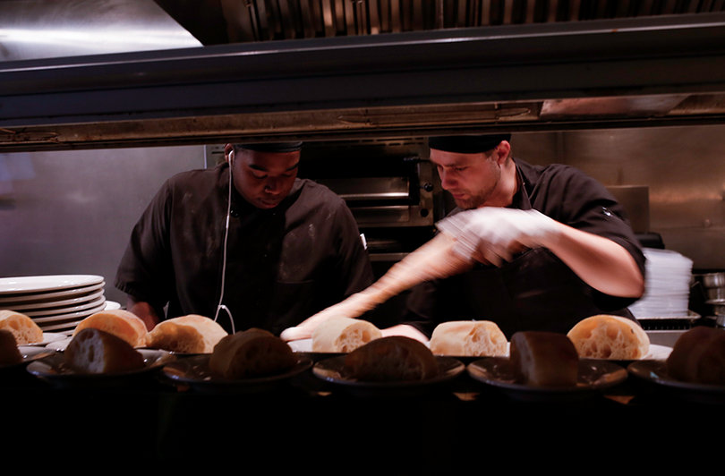 Demerris Bufford and Jesse Brzostowski, linecooks at Pastabilities, cut fresh bread for the lunch rush.