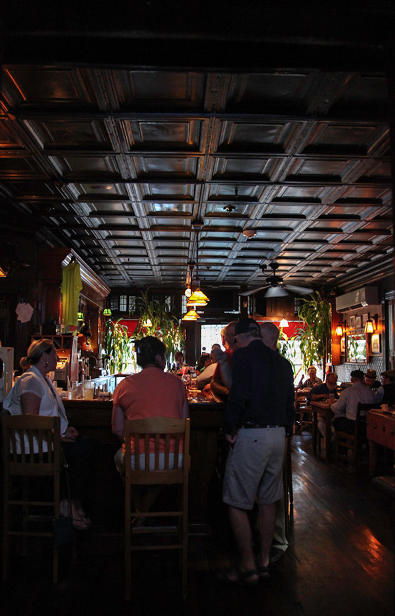 Customers sit at the bar waiting for their food and drinks, taking in Riley's welcoming atmosphere. 