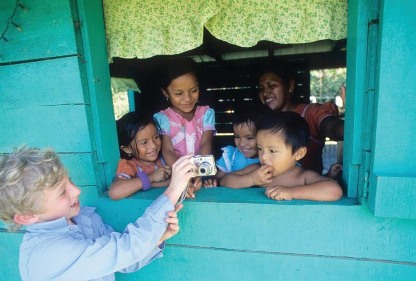 Chase Guttman, at the age of 9, shows his camera to a family in Punta Gorda, Belize, after taking their picture. As a travel photographer, Guttman has visited 48 countries.    