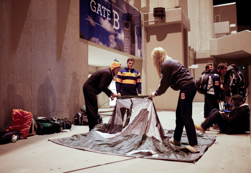(From left to right) Matt Lolarga, Matthew Deeb and Sarah Yelle set up their tent early Tuesday morning outside of Gate B of the Carrier Dome. Students began camping out around midnight for bus vouchers and tickets to Saturday's Syracuse vs. Notre Dame game at MetLife Stadium.