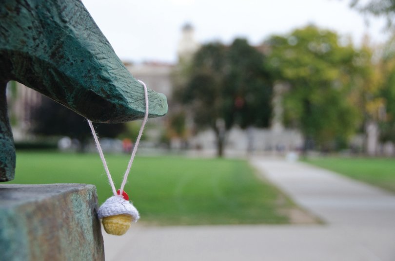 A lone crocheted cupcake hangs from a statue on the Quad. Starting Friday morning, students will see items such as this cupcake around campus as part of the art installation project of an environmental textile class.
