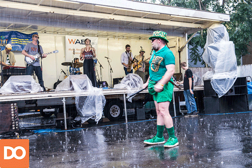 Sir Quala O’Smith dances in the rain while a rock band plays their set at the street fair.