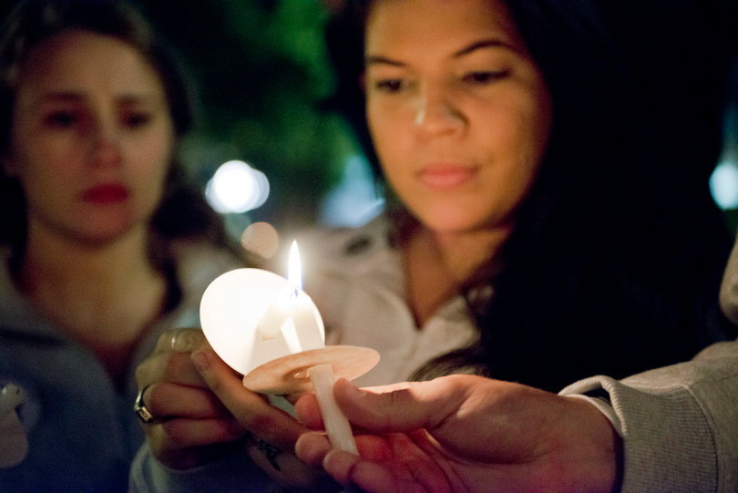 Alexandra Marie Figueroa, a senior dual major in anthropology and international relations and Remembrance Scholar, lights a candle at the Candle Light Vigil.