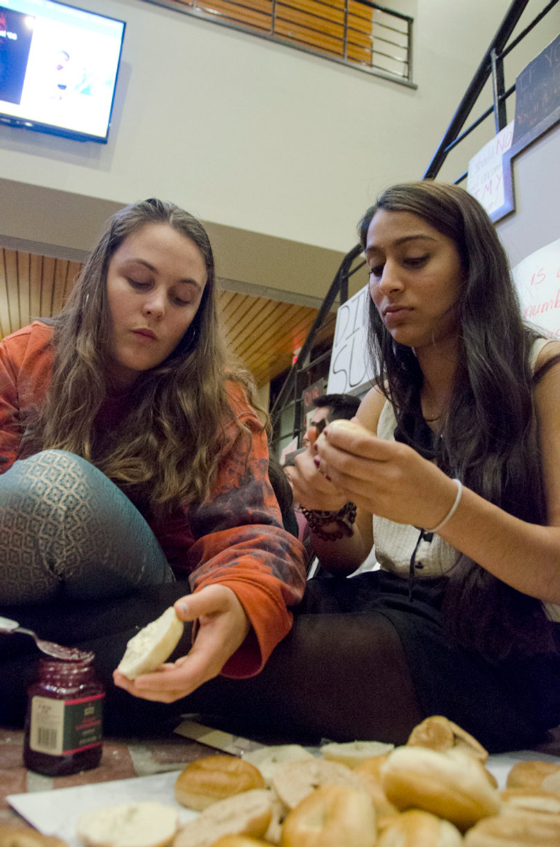 (From left) Heather Rounds, a junior magazine, middle eastern studies and citizenship and civic engagement triple major, and Ella Mendonsa, a senior political science and public policy dual major, help make peanut butter and jelly sandwiches to share with fellow DAT Rally protesters during a staged sit-in in the Crouse-Hinds Hall lobby.