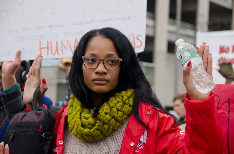 Ayania Wellington, a senior broadcast and digital journalism major, holds her hands up as part of the March for Mike Brown on Monday. Protesters chanted "Hands up, don't shoot," during the event.
