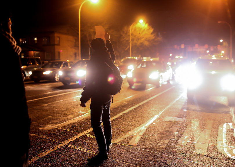 A protester holds up a 
"Don't Shoot" sign to the cars behind the group of marchers.