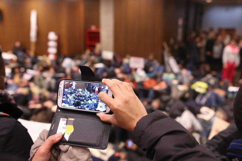 A student takes a photograph on their smartphone of the "die-in" that was held by protesters as part of the "March for Justice" on Monday.