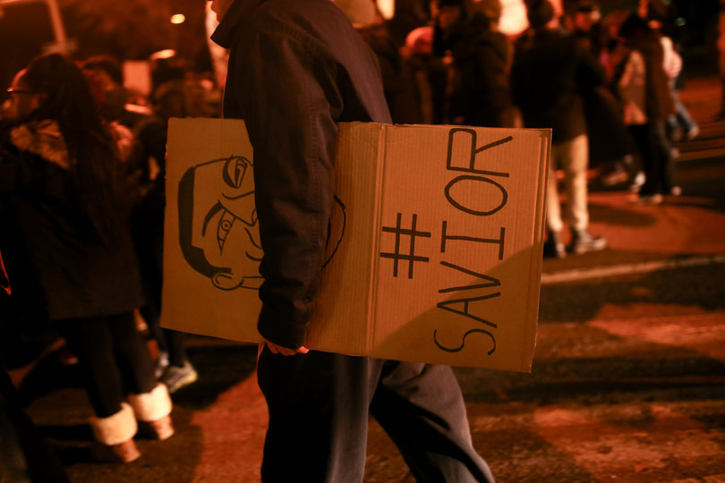 A marcher cradles a "#Savior" sign in honor of those who have died due to police brutality.