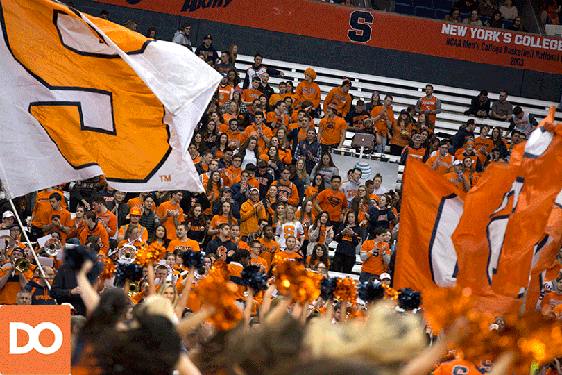 The SU cheerleading team carries flags spelling out "Cuse" during a stoppage in play.