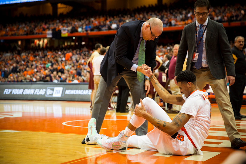 Trainer Brad Pike helps McCullough up. The freshman will be re-evaluated Monday, according to SU Athletics.