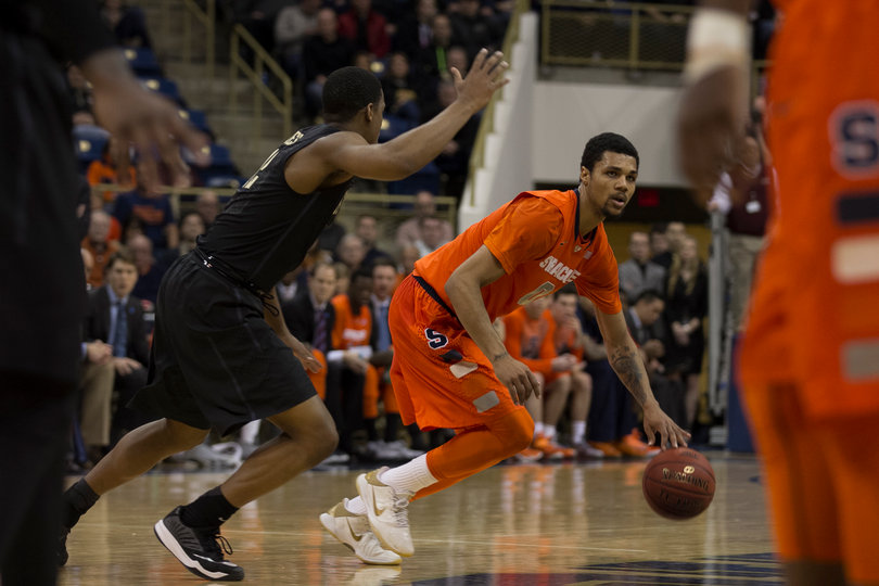 SU forward Michael Gbinije looks for a teammate while dribbling up top.