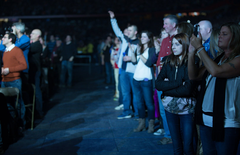 Audience members watch and take photos as Joel performs onstage.