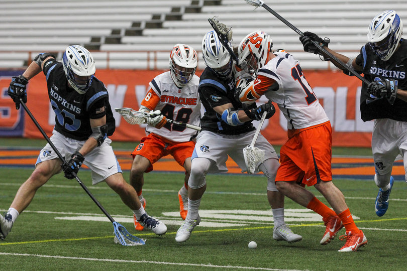 Syracuse attack Dylan Donahue pushes away a JHU player as a Blue Jay goes to scoop up the ground ball.