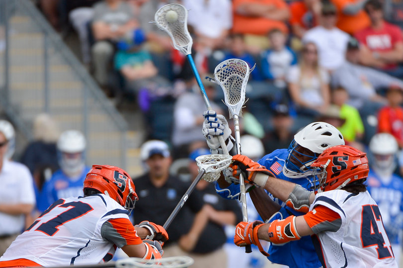 Jones fires a shot toward the net as SU's Joe Gillis and Sean Young contest.