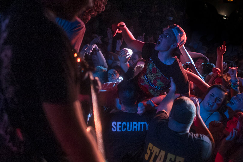 An audience member is helped by security staff members as he crowdsurfs. Crowdsurfing and moshing happened throughout the sets of both Knuckle Puck and Real Friends.